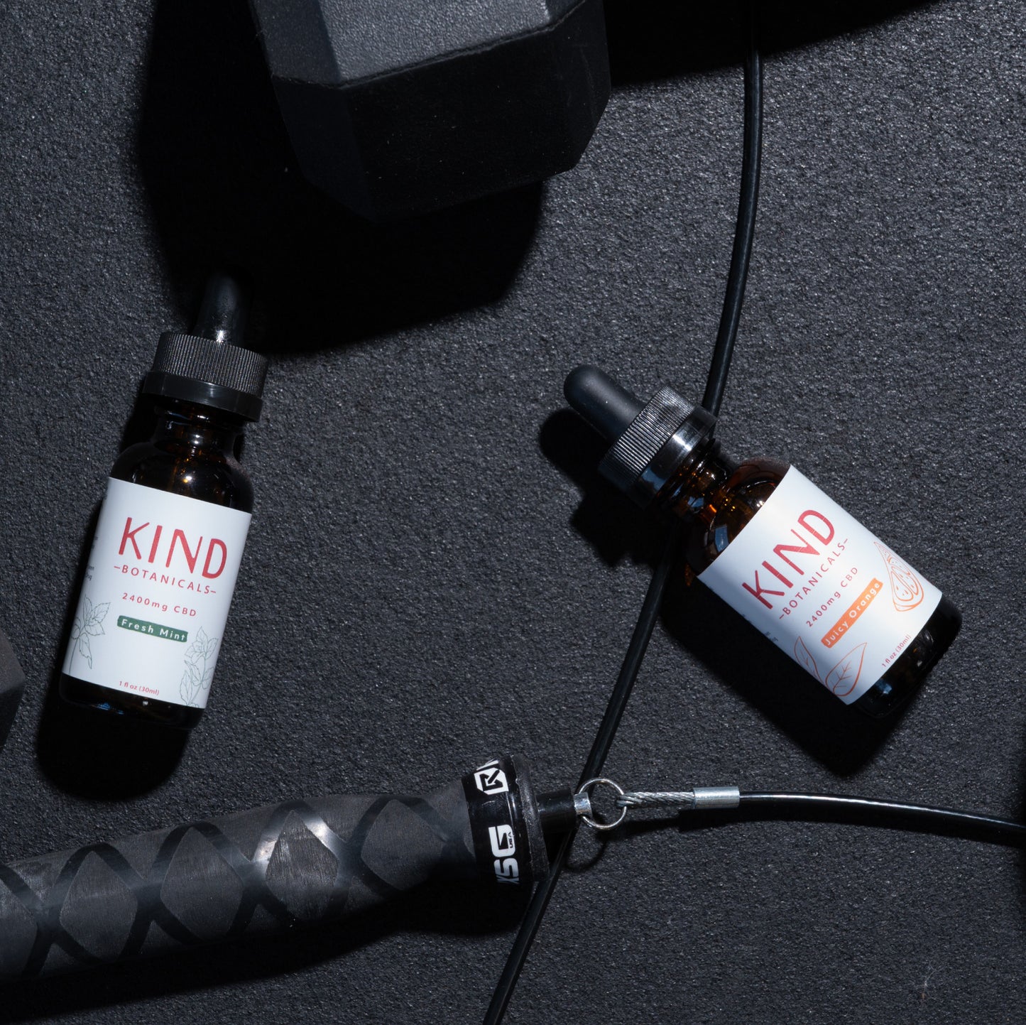 Kind CBD orange and mint Tincture on gym floor with weights