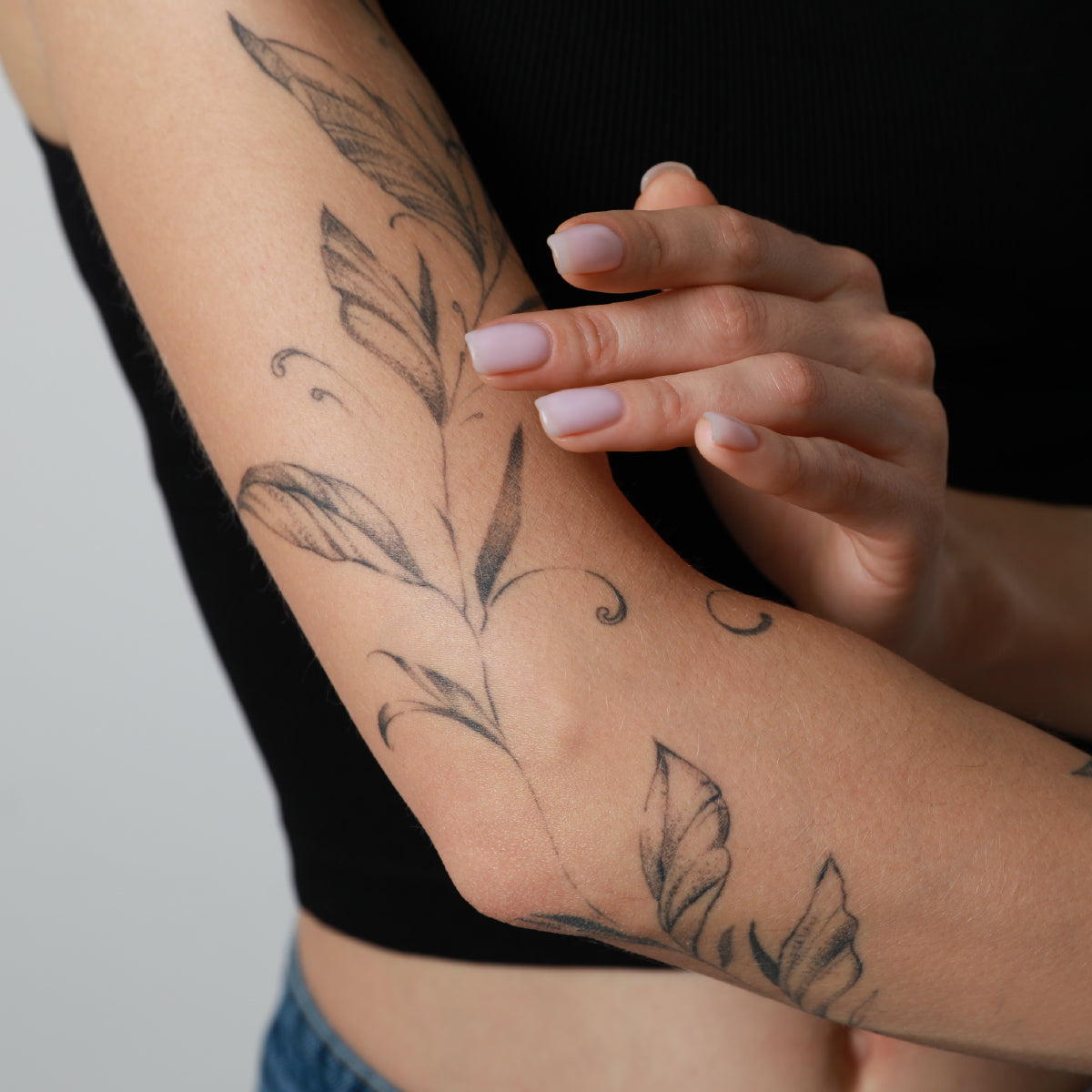 Person with floral tattoos on their arm against a neutral background