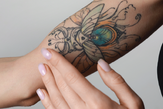 Women putting KIND tattoo balm on arm with tattoo