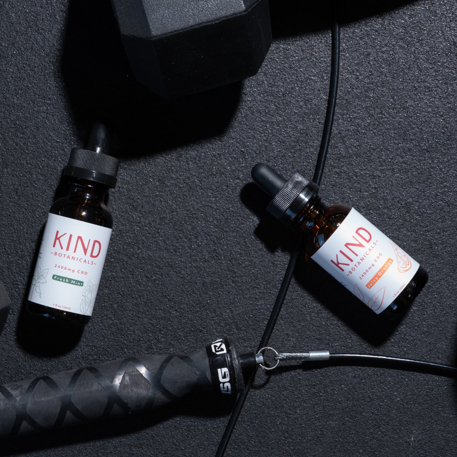 Kind CBD orange and mint Tincture on gym floor with weights 