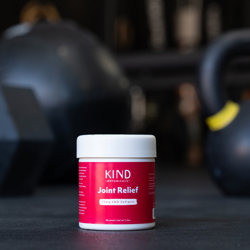 Container of Kind Formulas Joint Relief on a gym floor with kettlebells in the background
