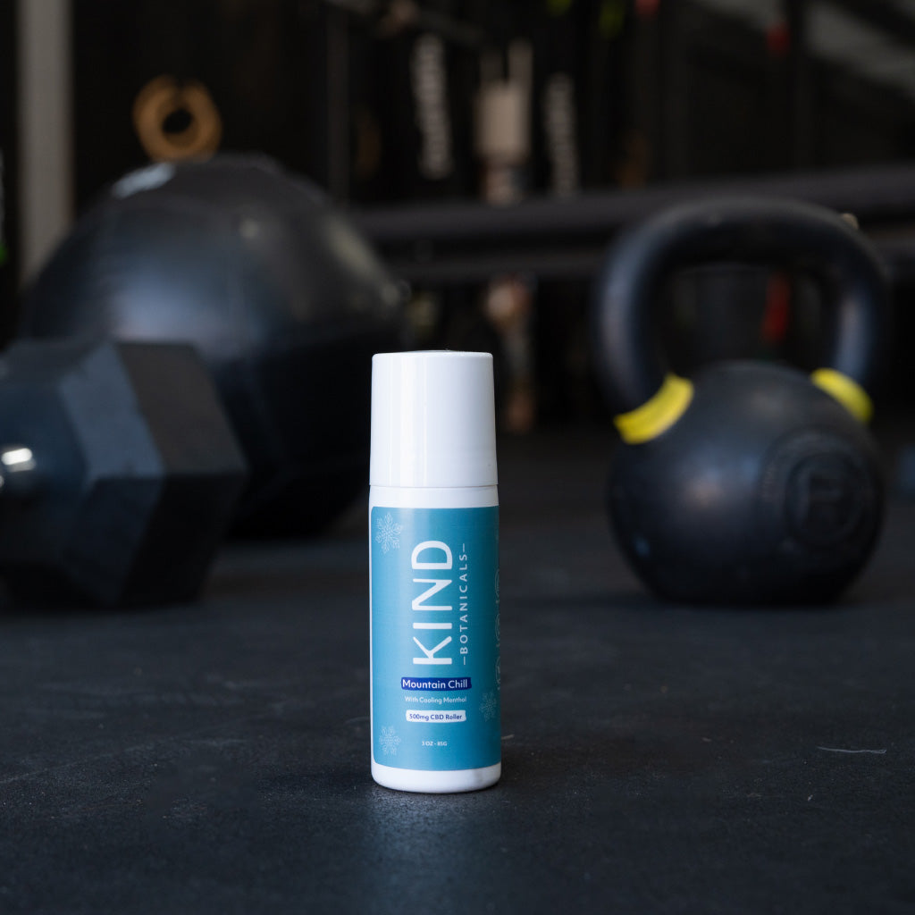 KIND roll on relief on a dark surface with kettlebells in the background