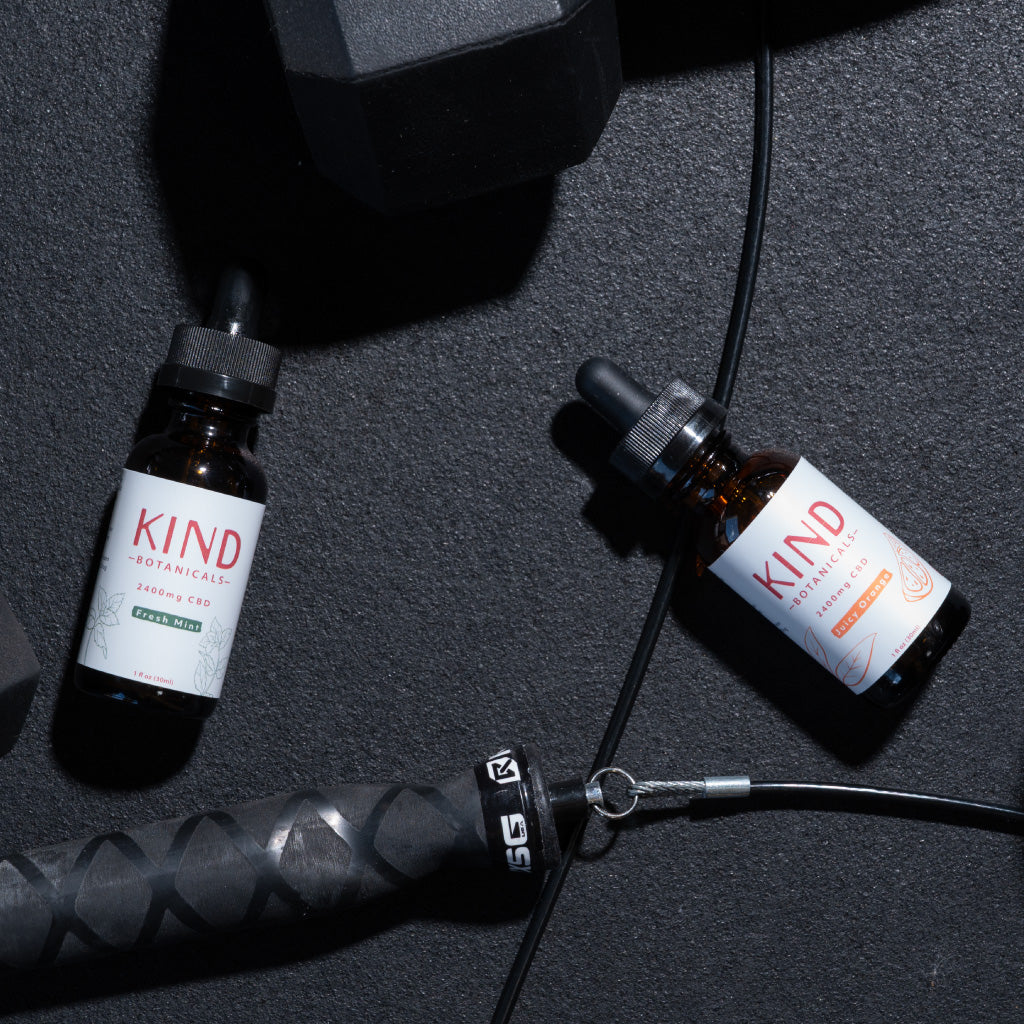 Two bottles of Kind Botanicals on a dark surface with a black background