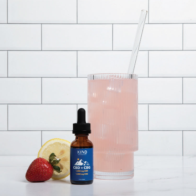 CBD + CBG tincture sitting on a table next to a glass of lemonade 