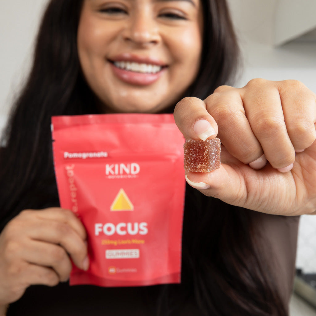 Person holding a red KIND Focus packet and a gummy bear.
