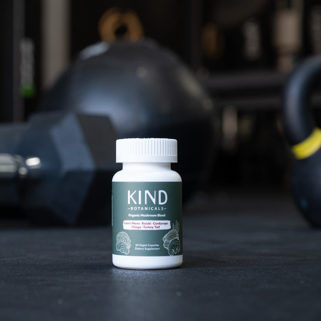 Bottle of KIND Botanicals supplement with gym equipment in the background
