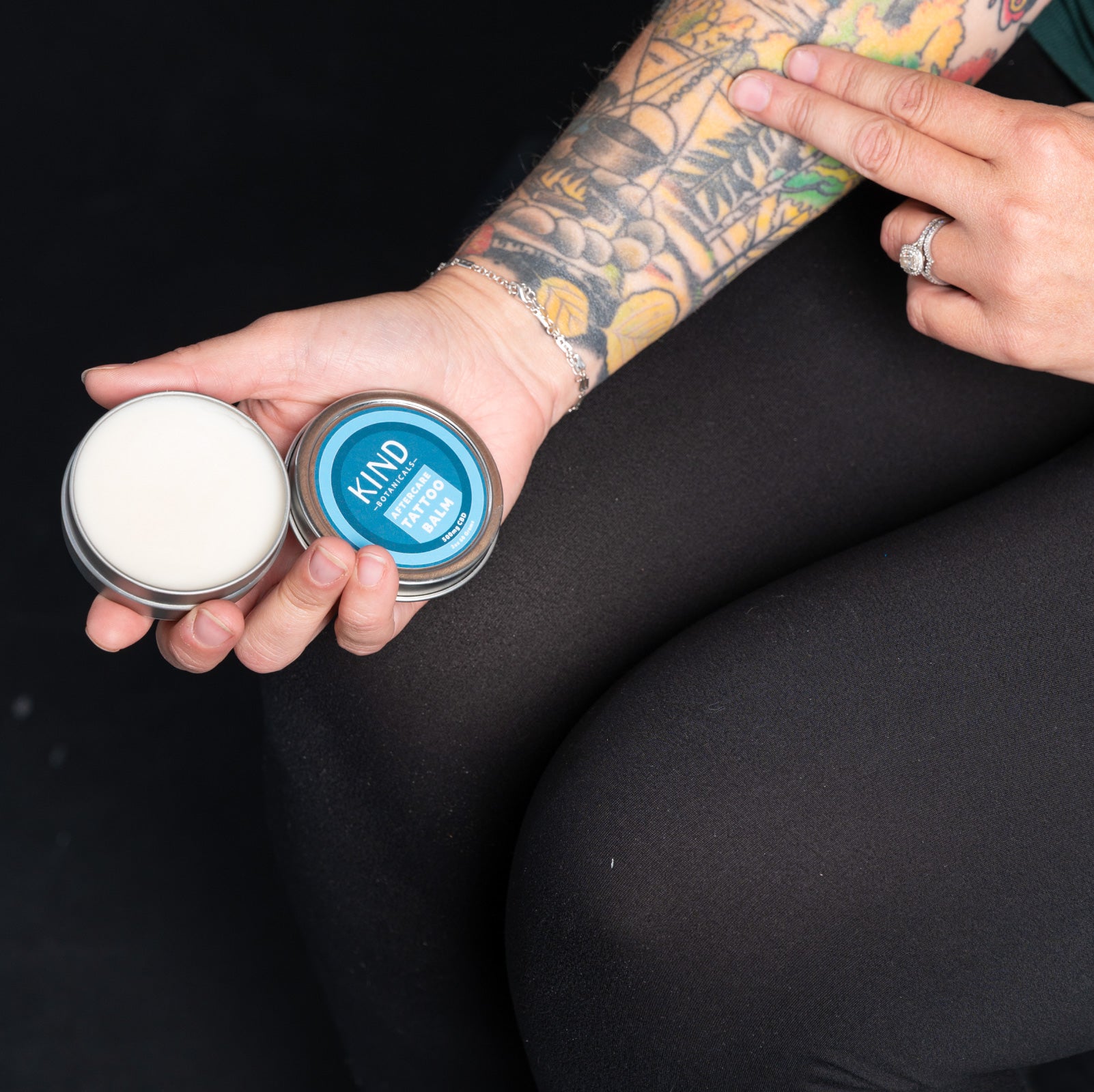 women putting on KIND tattoo balm on tattoo in gym